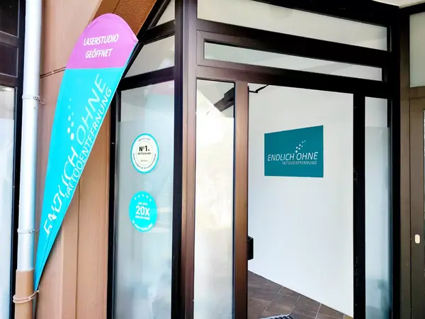 Eingang zu einem modernen Laserstudio für Tattooentfernung mit Werbebanner und Logo.